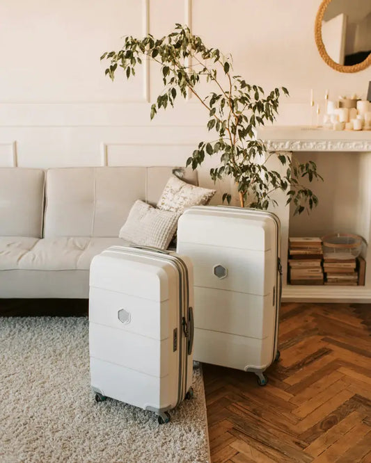 Two white hard-shell suitcases in a neutral living room.
